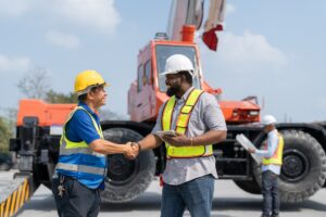 Asian Senior foreman handshake with African American engineer rent crane truck in construction site