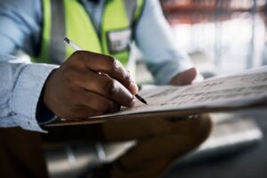 Shot of an unrecognisable builder filling out paperwork at a construction site